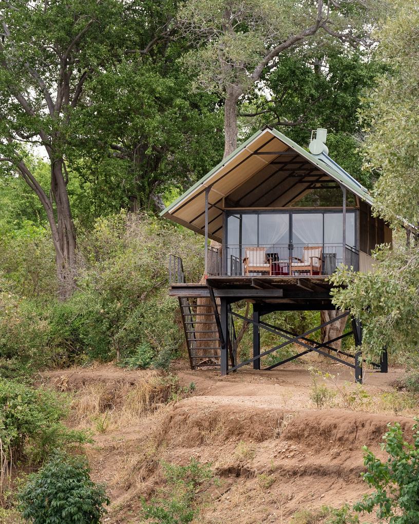 Elevated thatched chalet on stilts above the riverbed at Kavinga Safari Camp, Mana Pools.
