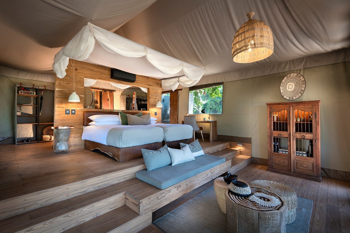 Tented bedroom with a canopy bed and wooden deck at Nyamatusi Camp.