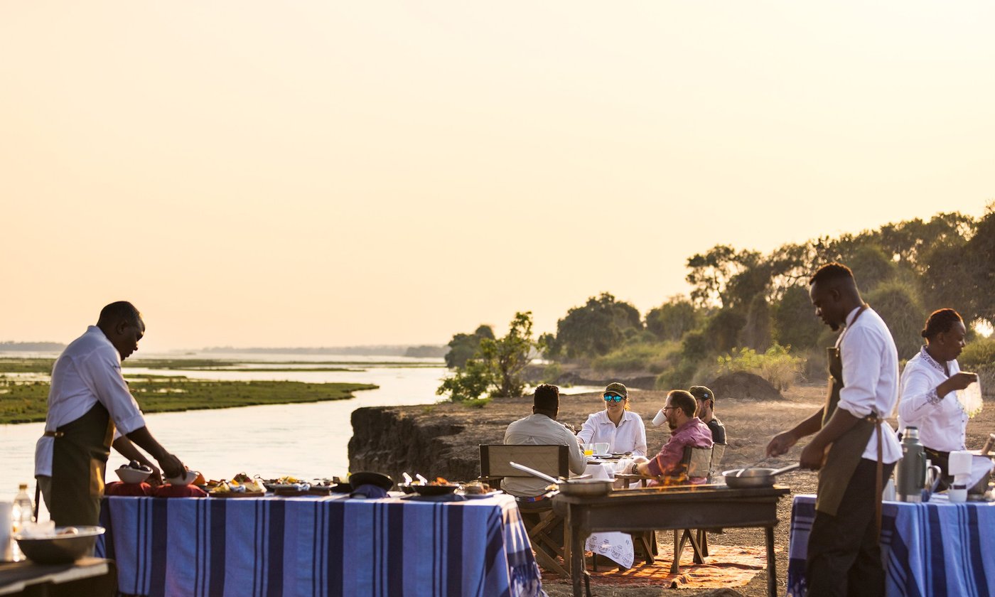 Private dining set on rocks above the river at Tembo Plains Camp.