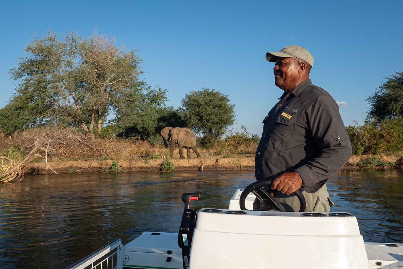 Boat safari passing an elephant on the riverbank at Wilderness Chikwenya.